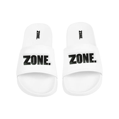 Zone sine hvite sandaler med svart preget sone-logo på foran og en liten logo i hæl-området. Sandalene er tilgjengelig i flere størrelser.